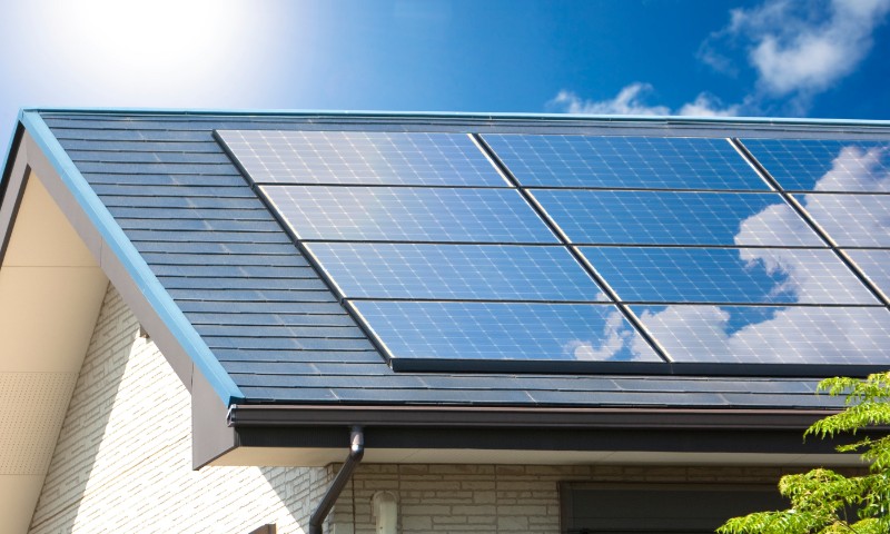 太陽に照らされる住宅の屋根に設置された太陽光パネル
